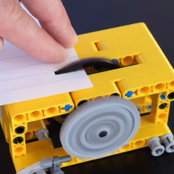 Пилка, повністю зібрана з LEGO, ледь справляється з папером.
